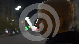 Portrait of sad lonely boy standing on city street at night, adoption center