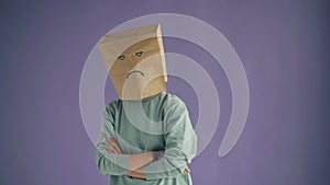 Portrait of sad person with paper bag on face standing with arms crossed