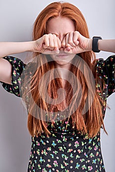 Portrait of sad redhead woman crying, rubbing eyes after tears, isolated on white