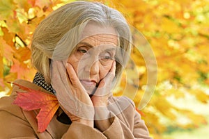 Portrait of sad senior beautiful woman in autumnal park
