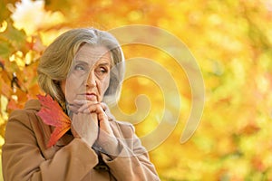 Portrait of sad senior beautiful woman in autumnal park