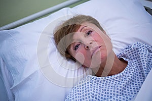 Portrait of sad senior patient lying on a bed