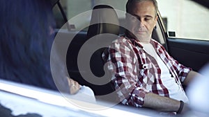 Portrait of sad serious Caucasian man sitting on driver's seat arguing with woman with crossed hands. Unhappy husband