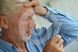 Portrait of sad sick senior man with pills