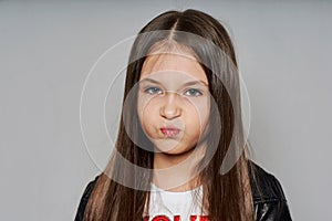 Portrait of a sad, unhappy little girl in a black leather jacket.