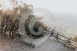 Portrait of a Sad or unhappy man sitting on a railing at Sunset