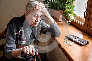 Portrait of a sad unhappy old woman counting money.