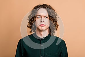 Portrait of sad upset gloomy young man wear green stylish clothes isolated on beige color background