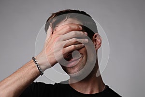 Portrait of sad young man covering his face with hand.Suicide thoughts.