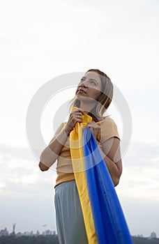 portrait of a sad young woman holding the Ukrainian flag in her hands