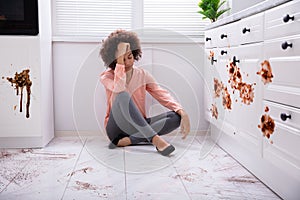 Sad Woman Sitting In Messy Kitchen