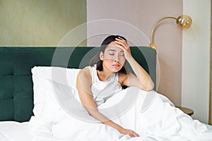 Portrait of sad young woman waking up, feeling bad, wants to sleep, wakes early morning, looking lazy and upset