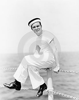 Portrait of a sailor sitting on the pole of a boat and smiling