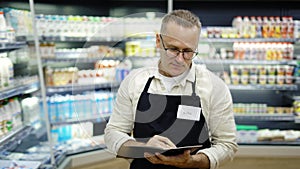 Portrait of a sales assistant in glasses with a notebook and a pencil in his hands in a grocery store. The concept of