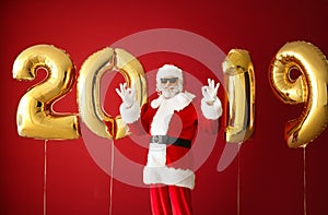 Portrait of Santa Claus with balloons in shape of figures 2019 on color background