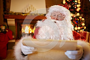 Portrait Santa Claus sitting and reading children wishes for Christmas.