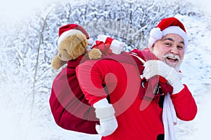 Portrait of Santa in the winter field. Santa Claus on Christmas Eve is carrying presents to children in a bag.