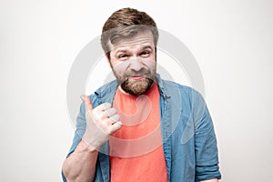 Portrait of a sarcastic, cunning bearded man showing thumb up gesture, on a white background