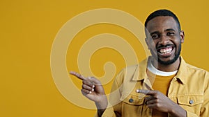 Portrait of satisfied African American man pointing sidewards and laughing looking at camera