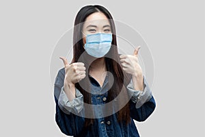 Portrét spokojený krásný asijský mladá žena chirurgický zdravotní v modrý bunda stojící palec nahoru a 