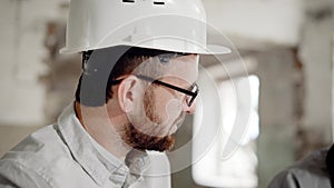 Portrait of a satisfied businessman in a helmet on his head, who discusses the completion of the construction site with