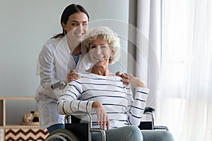 Portrait of satisfied elderly patient in wheelchair and caring caregiver