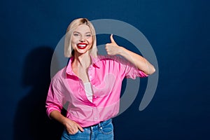 Portrait of satisfied girl with bob hairdo wear stylish shirt showing thumb up hold arm in pocket isolated on dark blue