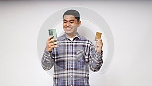 Portrait of satisfied happy Asian young man holding smart phone and credit card photo