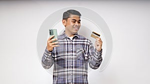 Portrait of satisfied happy Asian young man holding smart phone and credit card photo