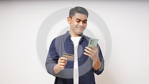 Happy Asian young man holding smart phone and credit card photo