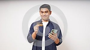 Happy Asian young man holding smart phone and credit card photo