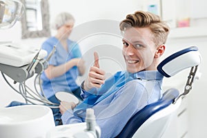 Portrait of satisfied man visiting dentist giving thumbs up in the dental clinic