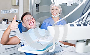 Portrait of satisfied man visiting dentist giving thumbs up