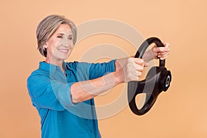 Portrait of satisfied person wear stylish shirt hold steering wheel look empty space buy new car isolated on beige color