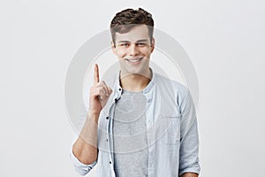 Satisfied and pleased caucasian customer pointing with index finger up at blank space over head for your advertisment photo