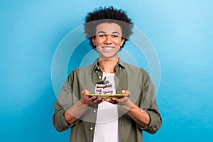 Portrait of satisfied positive guy perming coiffure wear khaki shirt hold plate with chocolate cake isolated on blue