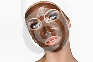 Portrait of a satisfied pretty girl biting chocolate bar and looking at camera isolated over white background. Close-up shot of