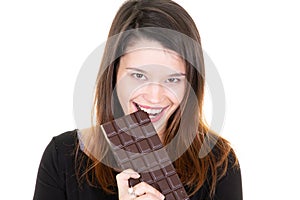 Portrait of a satisfied pretty girl biting chocolate bar smiling on white background