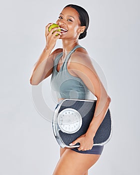 Portrait, scale and black woman eating apple on diet for weightloss, workout and health lifestyle. Fitness, nutrition