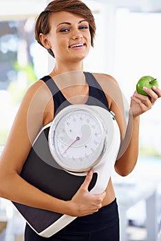 Portrait, scale and happy woman with apple for diet, nutrition or wellness with healthy body. Weight loss, smile and