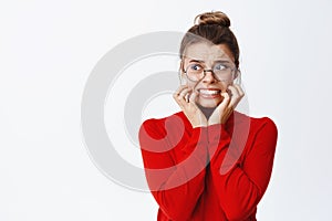 Portrait of scared businesswoman biting fingernails and looking left frightened, panicking and staring with fear at copy