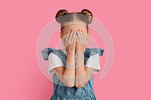 Portrait of scared little girl covering her face with hands