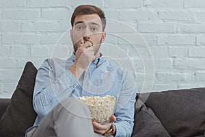 portrait of scared man with popcorn watching film