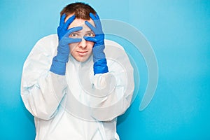 Portrait of scared man in protective suitt, medical mask and gloves against viruses and infections cover face by hand isolated on