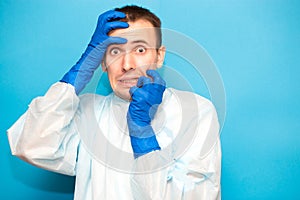 Portrait of scared man in protective suitt, medical mask and gloves against viruses and infections cover face by hand isolated on