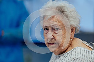 Portrait of scared senior patient on examination table in the hospital. Concept of fear and anxiety about health