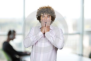 Portrait of scared shocked young man with curly hair.