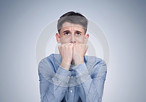 Portrait of a scared teenage boy, on a blue background