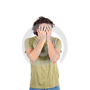 Portrait of scared young man, long curly hair style, looking through fingers as covers his face with hands to protect from any