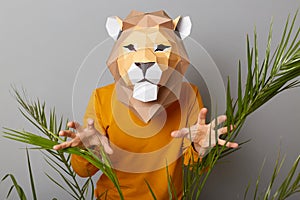 Portrait of scary anonymous man wearing lion mask and orange sweatshirt isolated over gray background, showing his paws, trying to